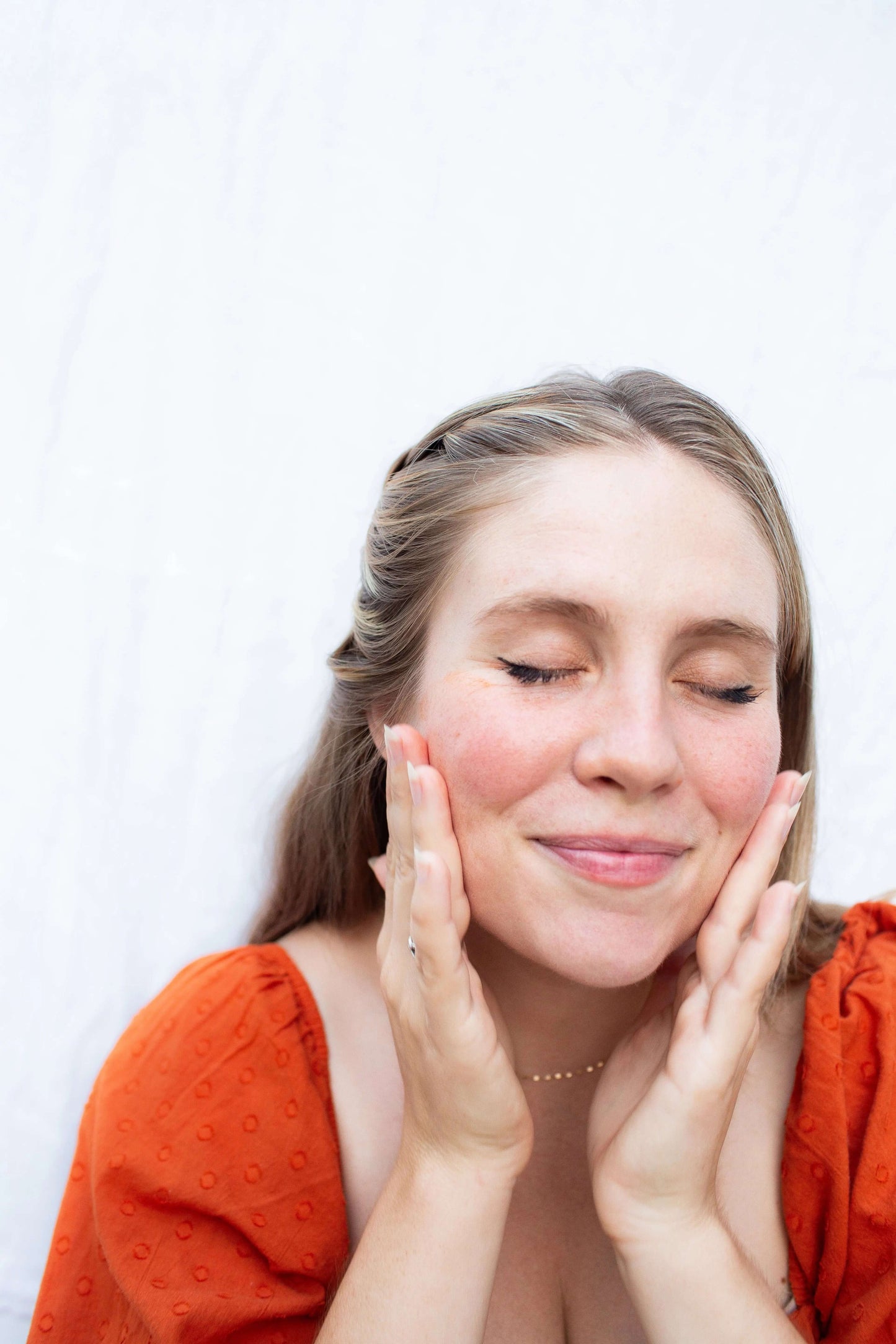 Woman applying Radiance Ritual Bundle Face Serum & Face Polish, showcasing radiant skin care routine.